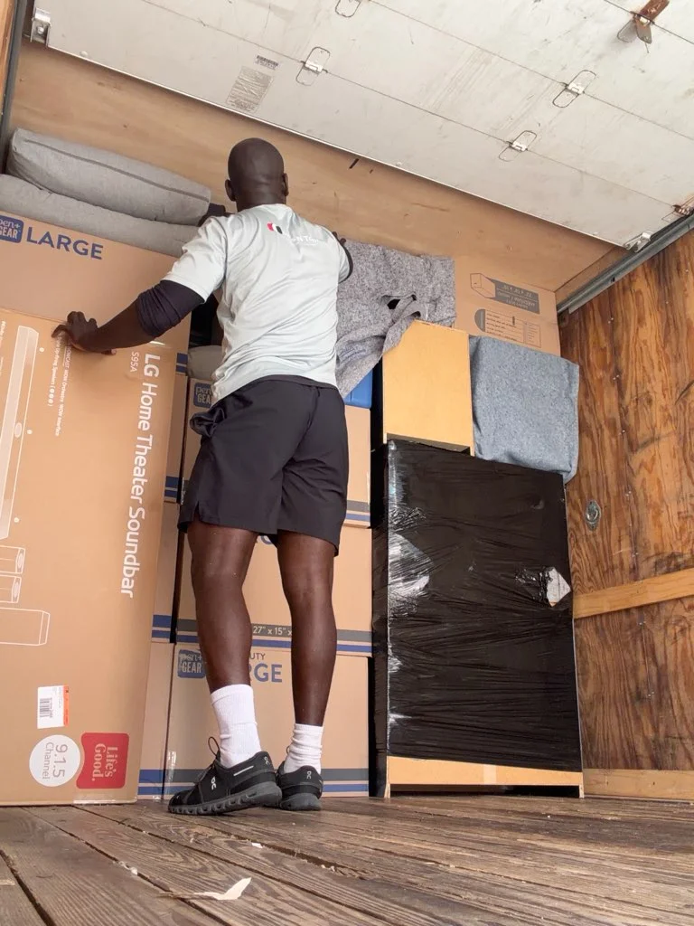 Moving crew organizing furniture and boxes in climate-controlled storage facility with protective wrapping
