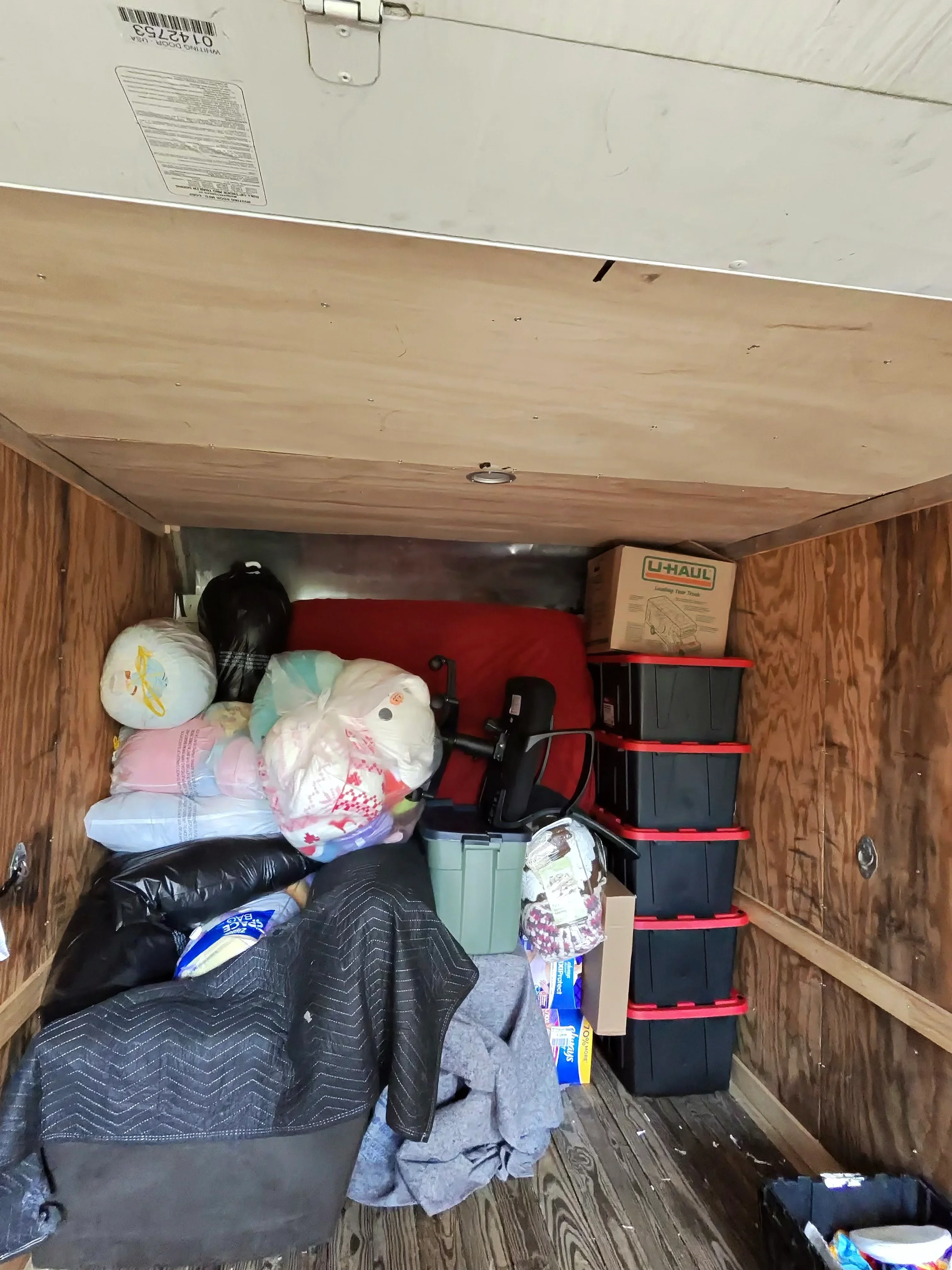 Moving truck interior with organized boxes, wrapped furniture, and household items ready for transport