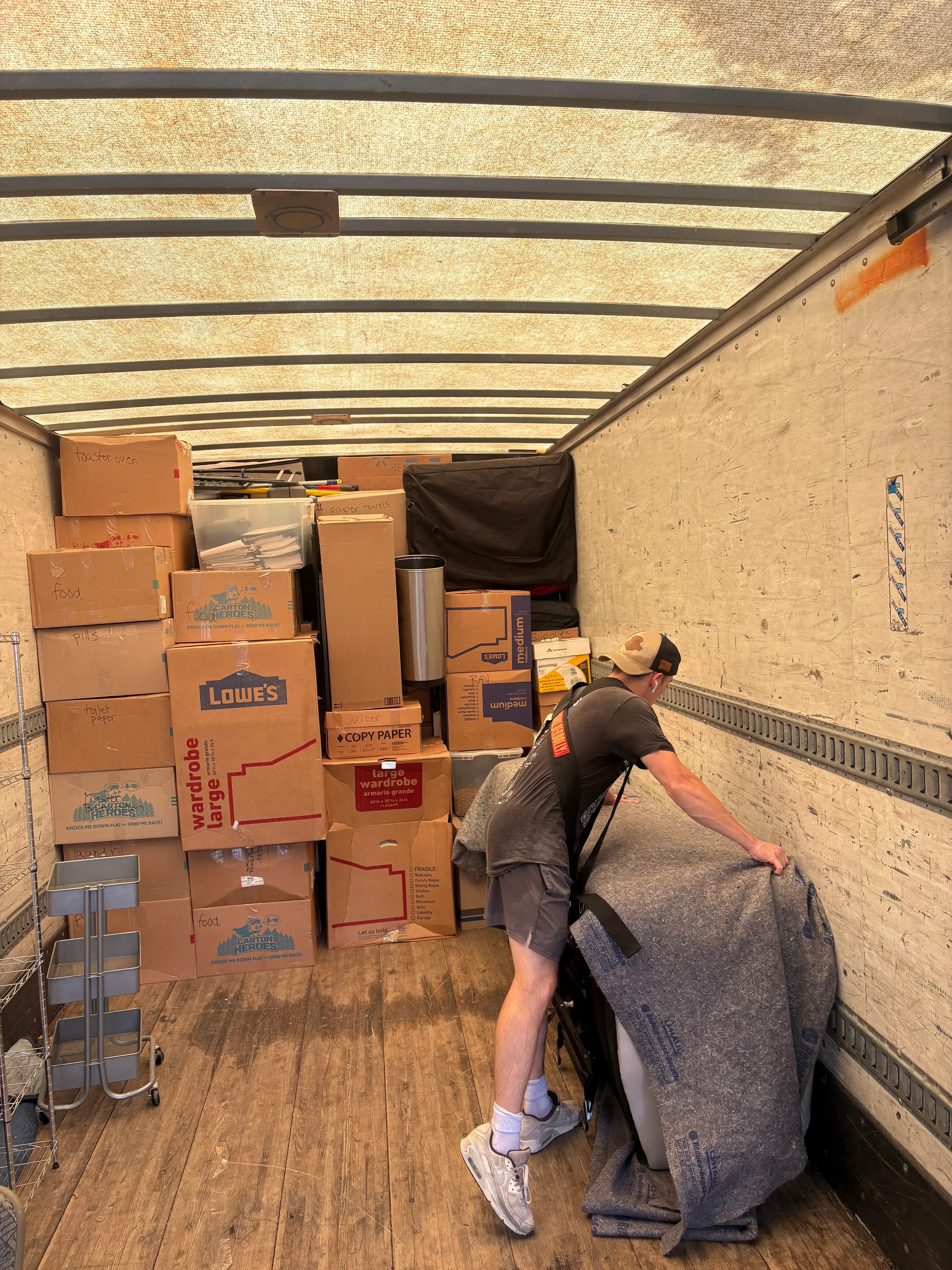 Moving crew loading cardboard boxes and household items into moving truck bed