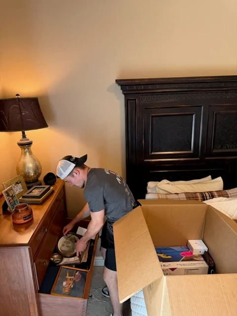 Moving crew member packing household items and linens into cardboard boxes