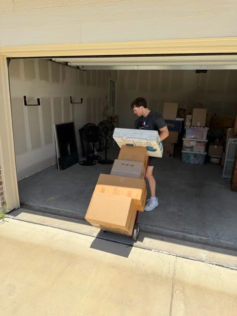 Moving crew packing boxes in garage with organized storage items and labeled cardboard boxes