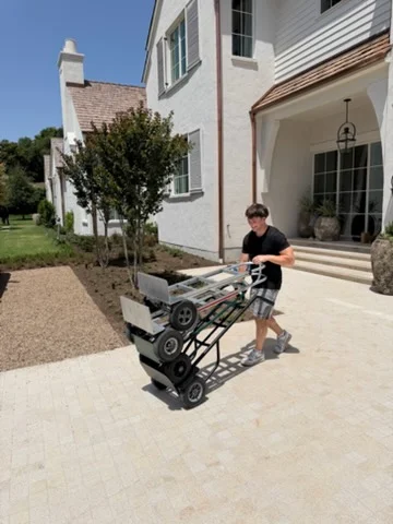 Moving crew with dolly transporting items across residential concrete patio