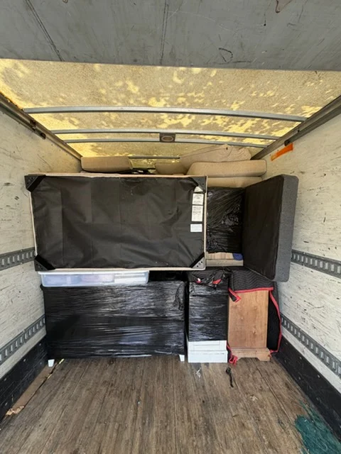 Moving truck interior with wrapped furniture, protective blankets, and metal tie-down straps