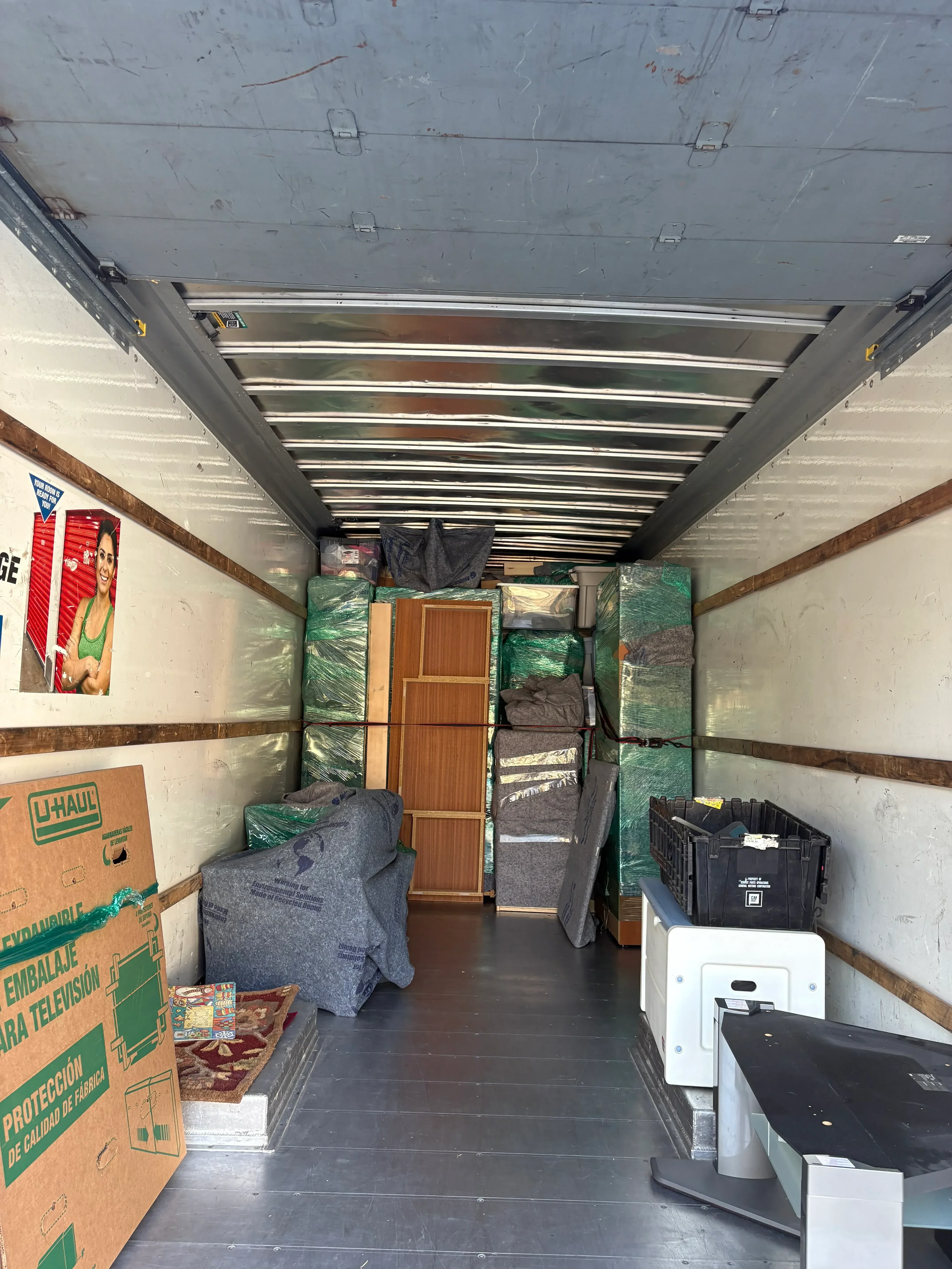 Interior of moving truck with wooden furniture, packed boxes, and secured household items