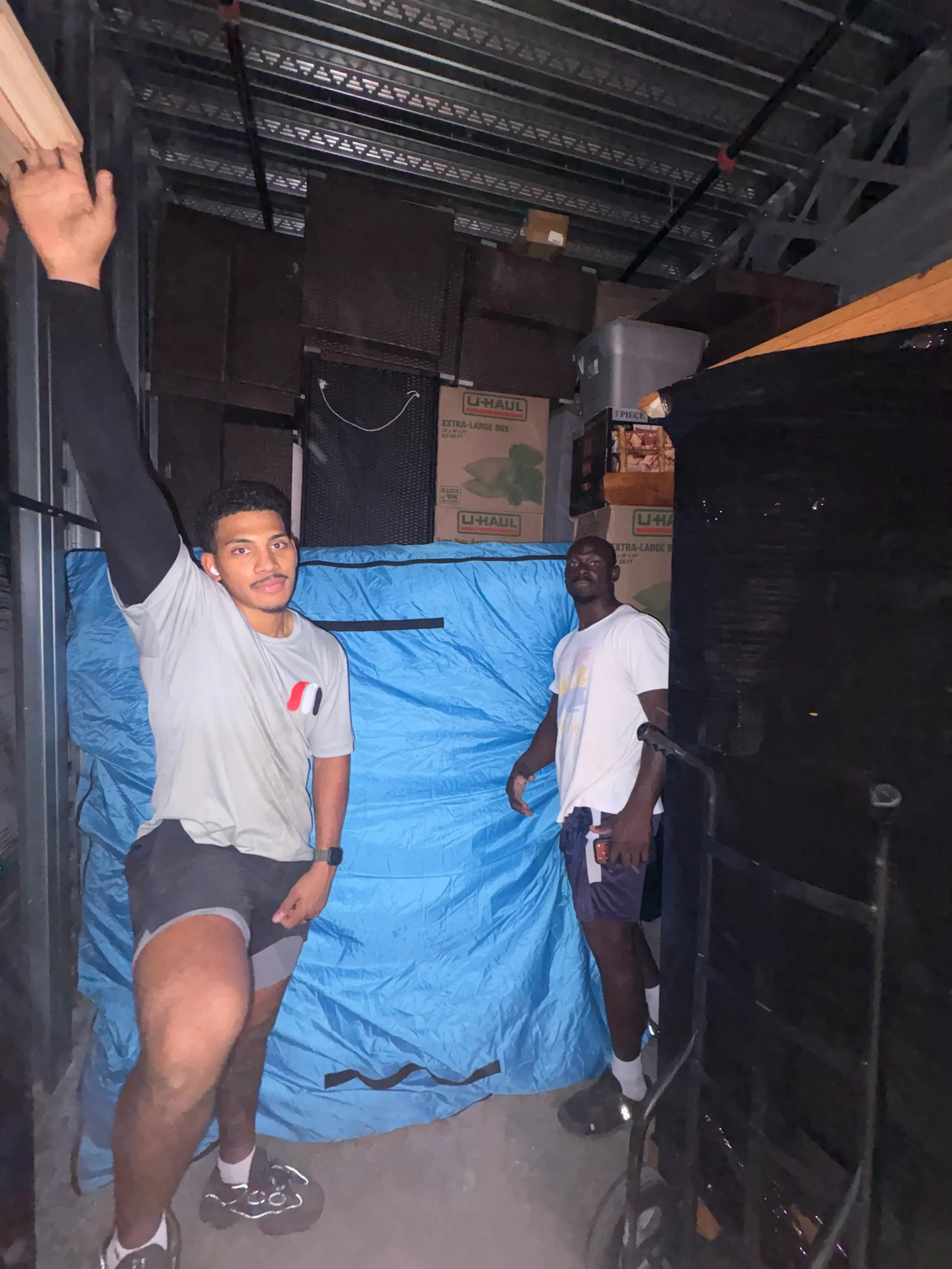 Moving crew loading household items with blue protective blankets in moving truck