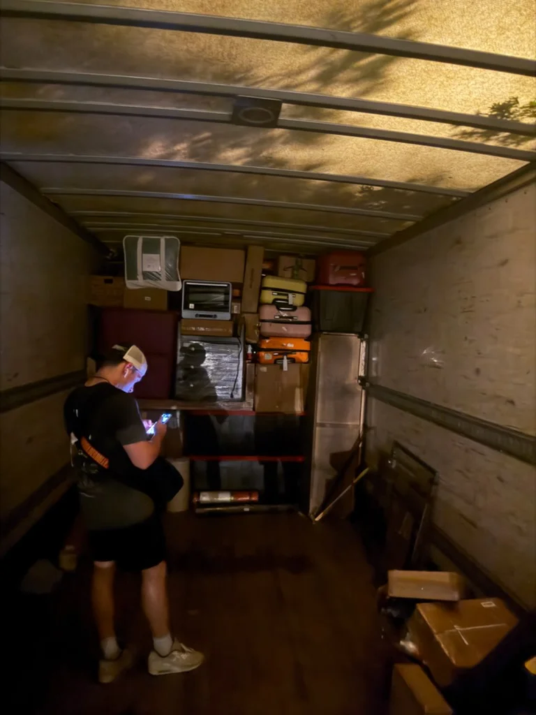 Moving truck interior with organized boxes, refrigerator, and household items loaded for transport