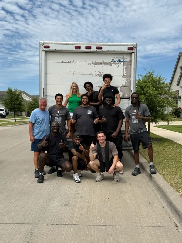 Moving crew team standing in front of loaded moving truck on residential driveway